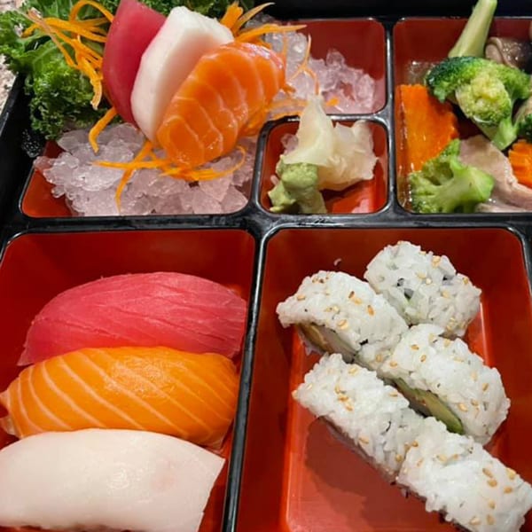 A Sushi Naiya bento box with sashimi, nigiri, California rolls, and steamed vegetables.