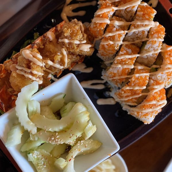 Sushi Naiya's fried lobster tail, sushi rolls with roe and sauce, and a side of pickled cucumbers.