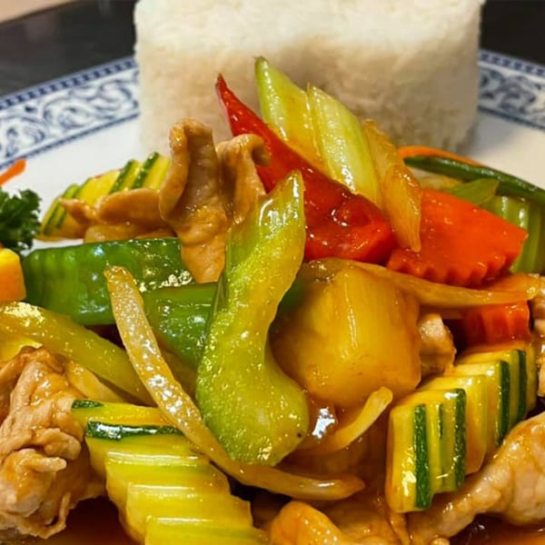 Stir-fried chicken with colorful bell peppers, zucchini, and onions, served with white rice.